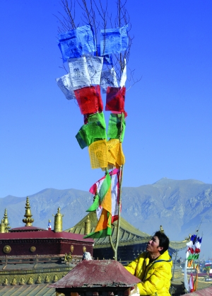 2月15日,在拉萨老城区大昭寺附近,一位藏族朋友在悬挂新的经幡祈福.